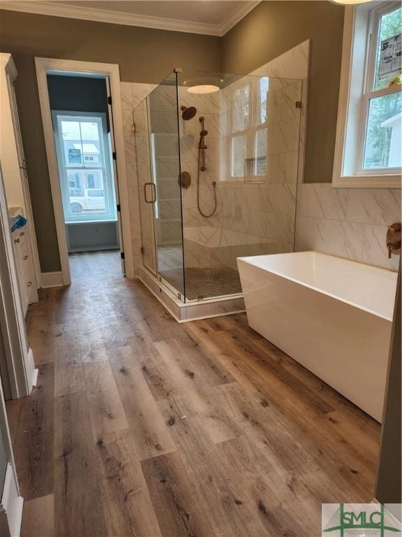 full bath with crown molding, a shower stall, a freestanding bath, and wood finished floors