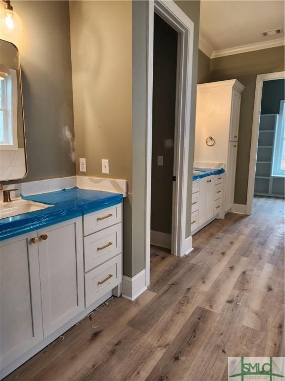 bathroom with baseboards, visible vents, ornamental molding, wood finished floors, and vanity