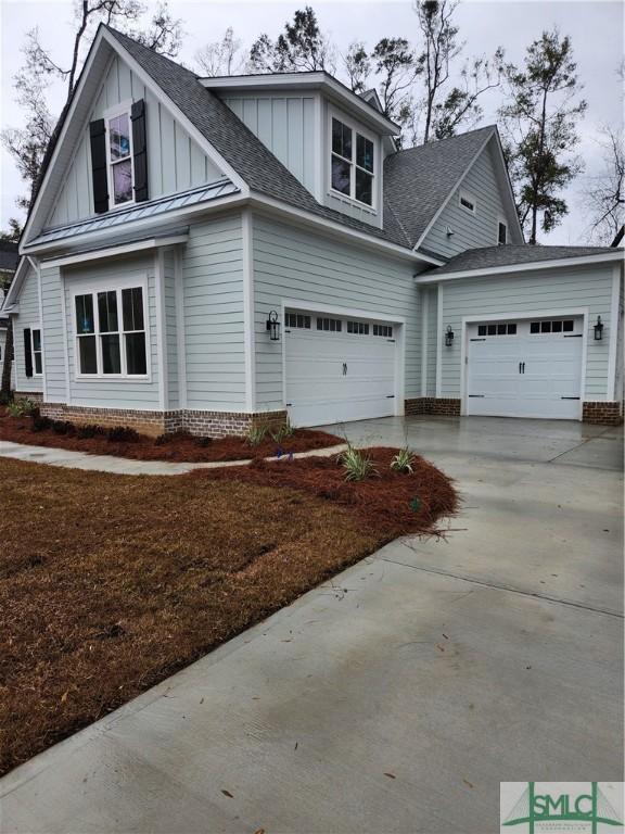 view of front of house featuring driveway, roof with shingles, an attached garage, a standing seam roof, and board and batten siding