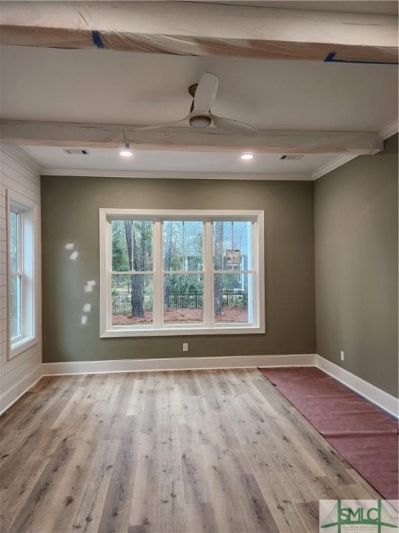 unfurnished room with baseboards, beamed ceiling, and wood finished floors