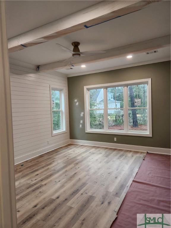 spare room featuring baseboards, visible vents, wood finished floors, and beamed ceiling