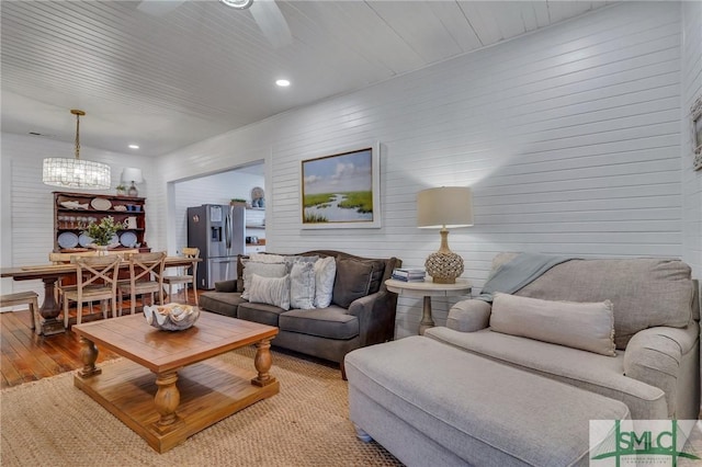 living room with ceiling fan with notable chandelier and light wood-type flooring