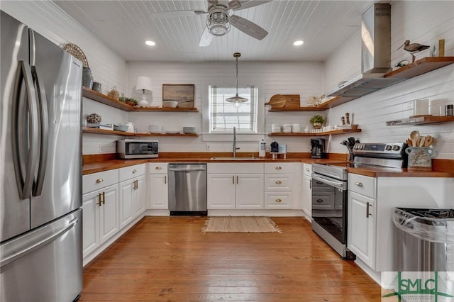 kitchen with sink, stainless steel appliances, wooden counters, pendant lighting, and white cabinets