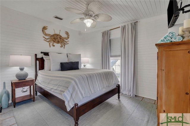 bedroom with ceiling fan and wooden walls