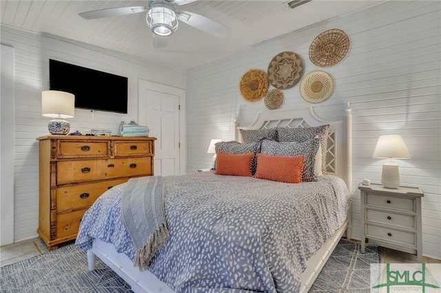 bedroom with ceiling fan and wooden walls