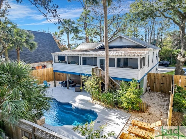 rear view of house featuring a sunroom and a fenced in pool