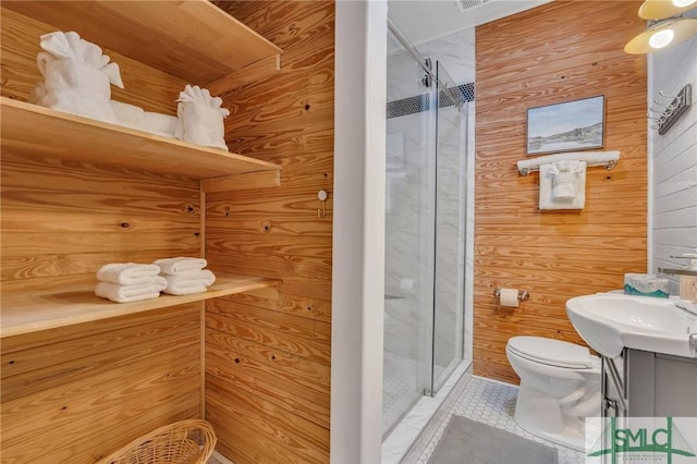 bathroom featuring tile patterned floors, vanity, a shower with door, toilet, and wood walls