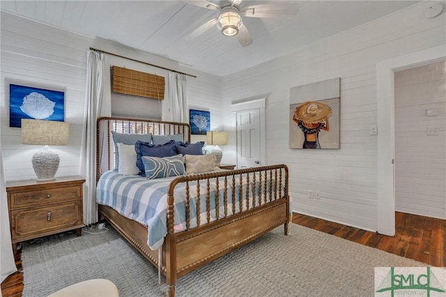 bedroom featuring ceiling fan, wood walls, and dark hardwood / wood-style flooring