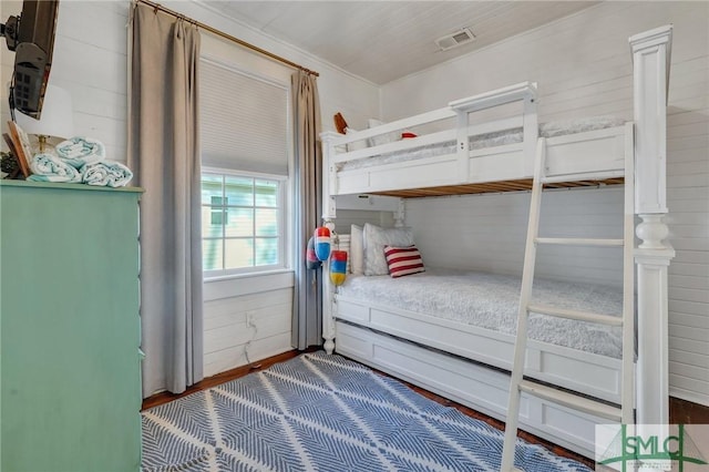 bedroom with wood-type flooring and wooden walls