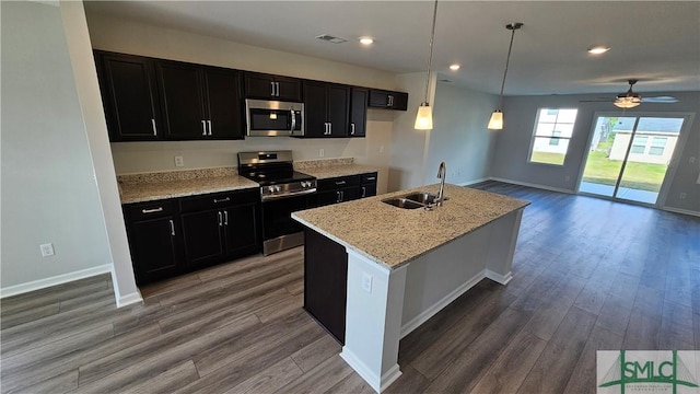 kitchen with dark hardwood / wood-style floors, sink, stainless steel appliances, and an island with sink