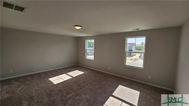 spare room featuring a wealth of natural light and dark carpet