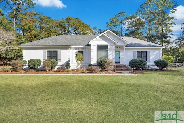 ranch-style home with a front yard and roof with shingles