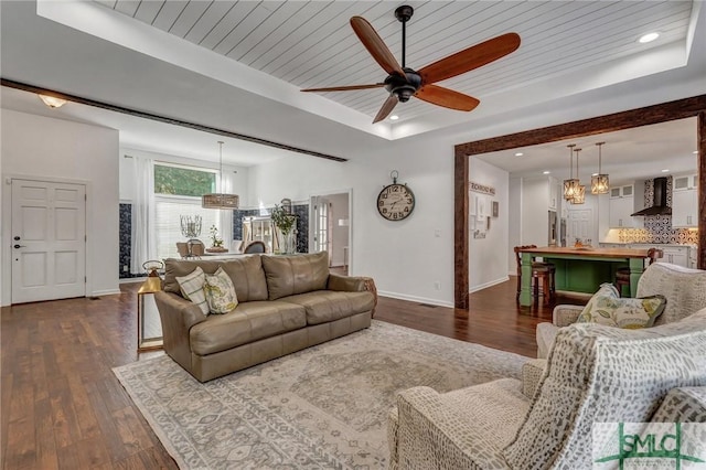 living room featuring ceiling fan, dark wood-type flooring, wood ceiling, and a tray ceiling