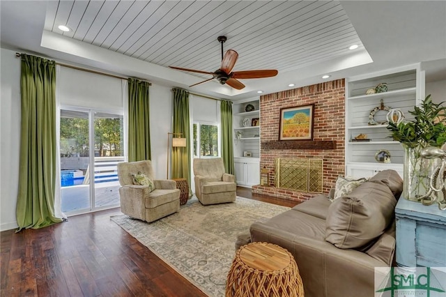 living area featuring a ceiling fan, a raised ceiling, built in shelves, and wood ceiling