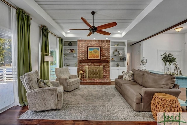 living area featuring a ceiling fan, built in features, a tray ceiling, wood finished floors, and wooden ceiling