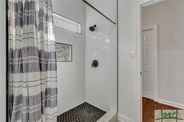 bathroom with tiled shower and wood finished floors