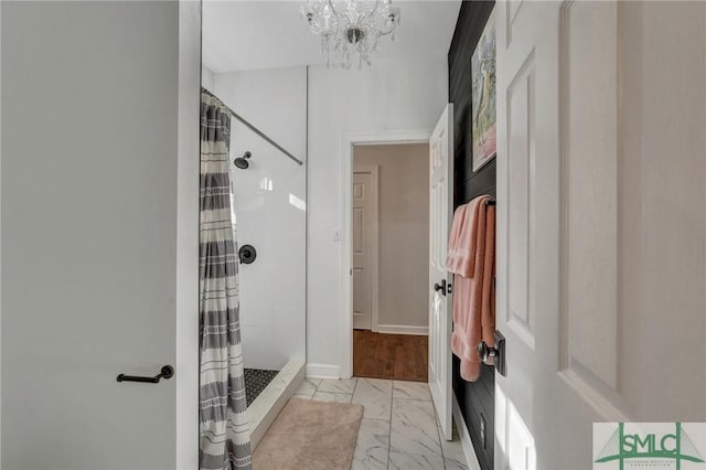 full bathroom with baseboards, marble finish floor, a chandelier, and a shower stall