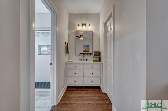 hallway featuring dark wood-type flooring, baseboards, and a sink