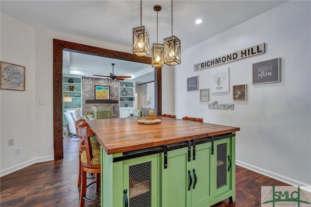 dining area with ceiling fan with notable chandelier, a fireplace, baseboards, and dark wood-style flooring