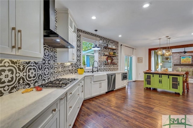 kitchen with dark wood-style floors, a sink, appliances with stainless steel finishes, wall chimney exhaust hood, and tasteful backsplash