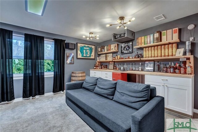 living room featuring visible vents, an inviting chandelier, baseboards, light colored carpet, and a dry bar