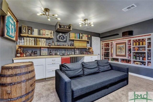 living room featuring visible vents, light carpet, a notable chandelier, and a bar