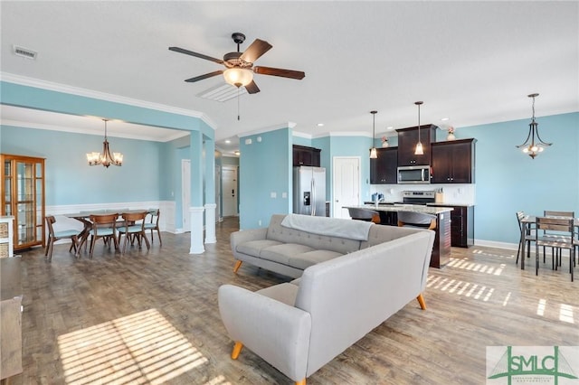 living room featuring sink, light hardwood / wood-style floors, ceiling fan with notable chandelier, and ornamental molding