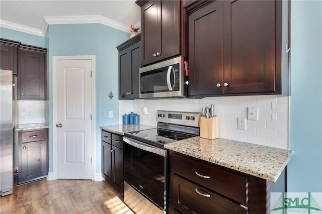 kitchen with light stone countertops, stainless steel appliances, light hardwood / wood-style flooring, decorative backsplash, and ornamental molding