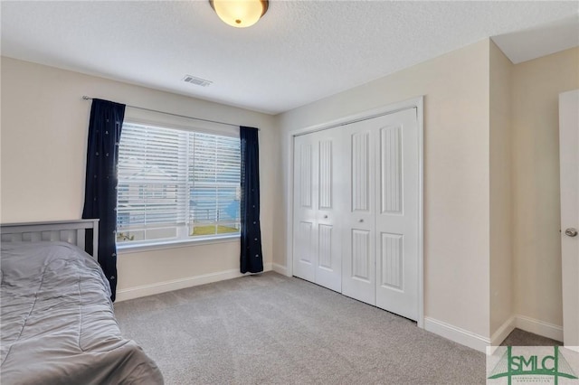 carpeted bedroom featuring a textured ceiling and a closet