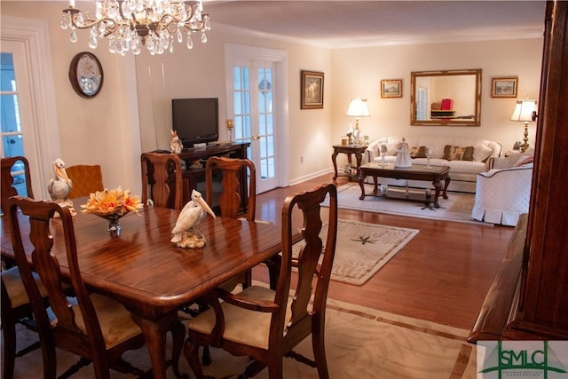 dining space with hardwood / wood-style floors, ornamental molding, and a notable chandelier