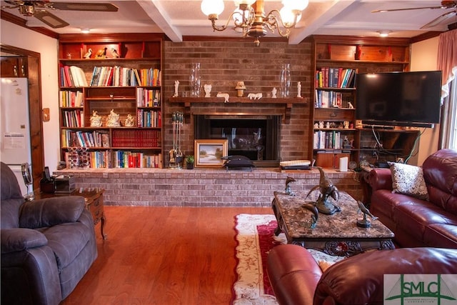 living room featuring beam ceiling, a fireplace, crown molding, and hardwood / wood-style floors