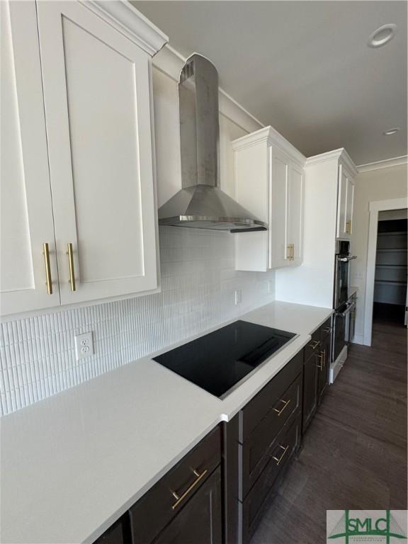 kitchen with wall chimney range hood, white cabinetry, backsplash, dark hardwood / wood-style floors, and black electric stovetop