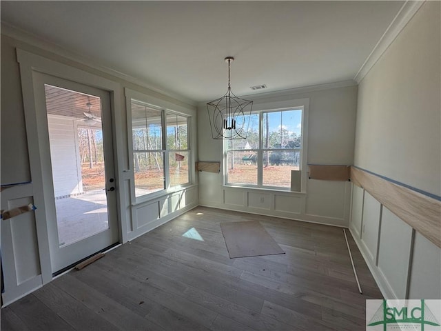 unfurnished dining area with dark hardwood / wood-style flooring, crown molding, and a chandelier