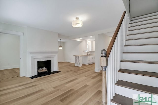 living room with sink, light wood-type flooring, and a fireplace