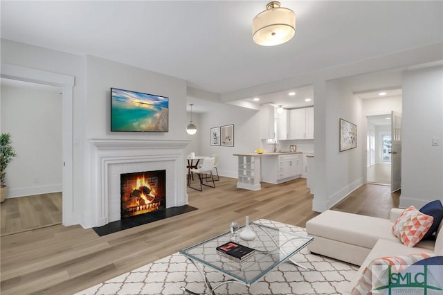 living room featuring light hardwood / wood-style floors, sink, and a fireplace