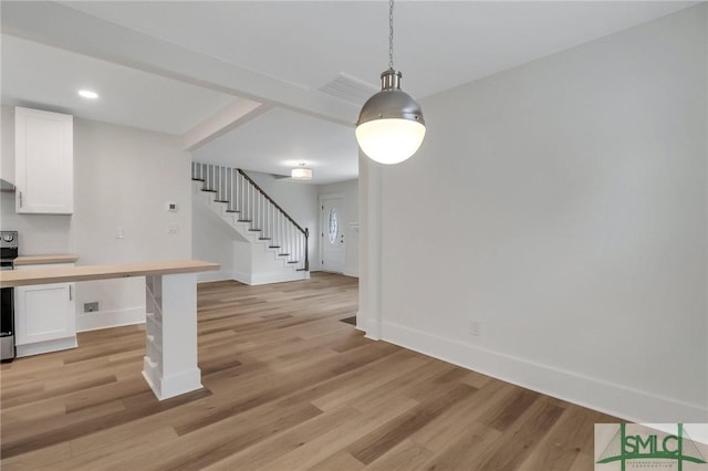 kitchen featuring white cabinets, light hardwood / wood-style floors, and decorative light fixtures