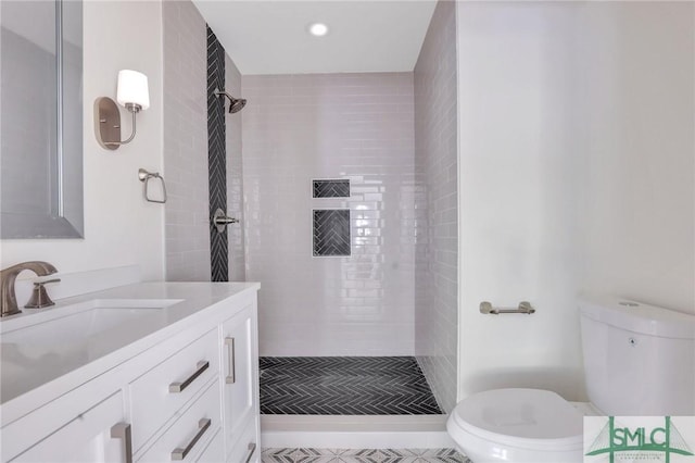 bathroom with tile patterned flooring, a tile shower, vanity, and toilet