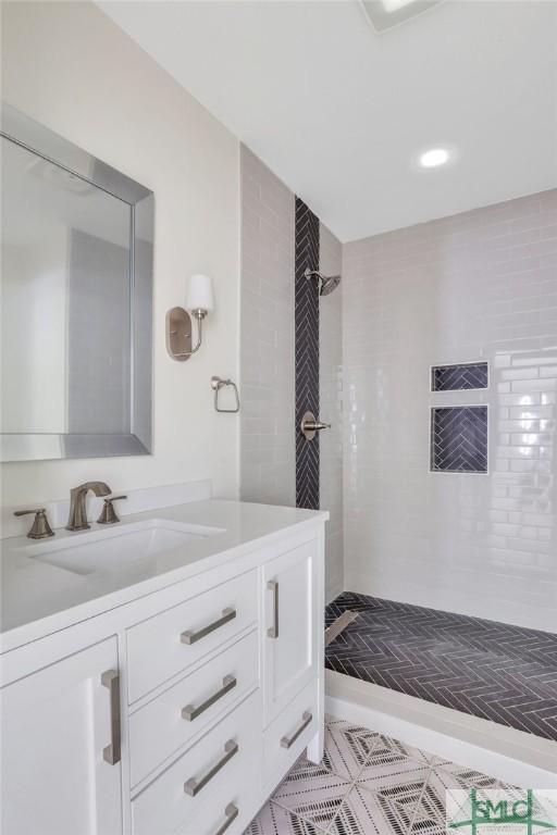 bathroom with a tile shower and vanity