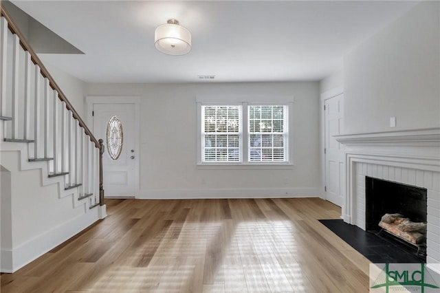 foyer featuring light hardwood / wood-style floors and a brick fireplace