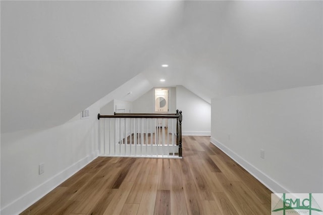 additional living space with wood-type flooring and vaulted ceiling