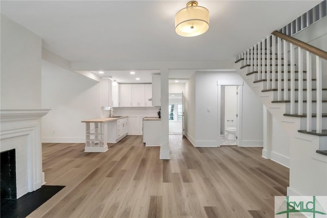 unfurnished living room with a brick fireplace, light hardwood / wood-style flooring, and sink