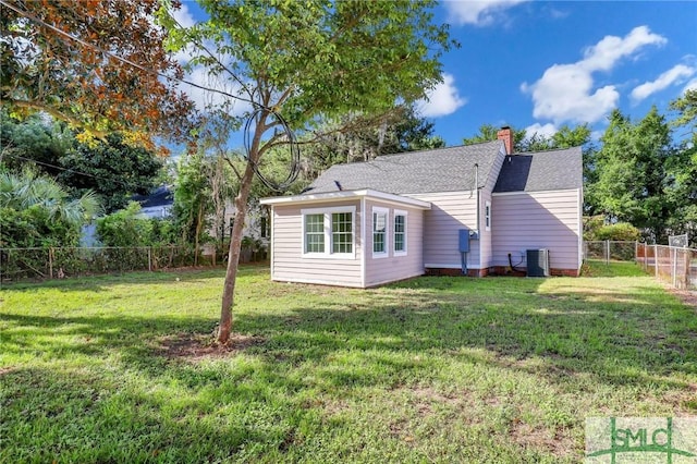 back of house with central AC unit and a lawn