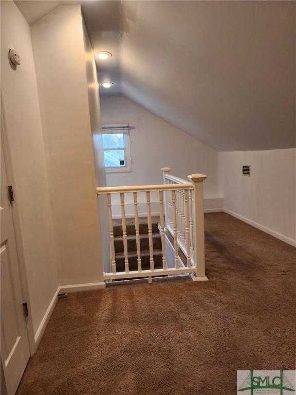 bonus room with lofted ceiling and dark colored carpet