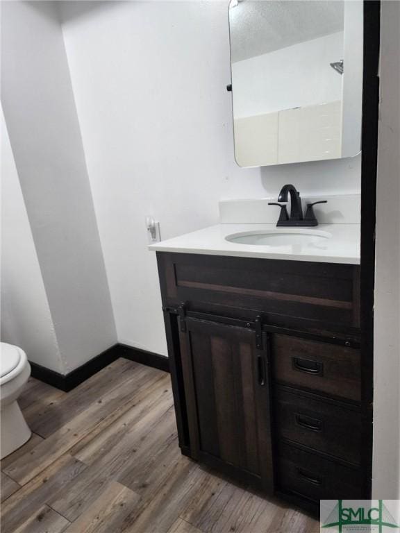 bathroom with hardwood / wood-style floors, vanity, and toilet