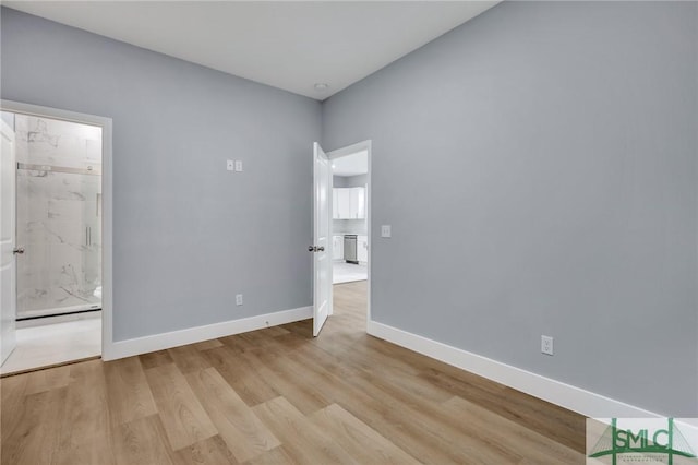 unfurnished bedroom with connected bathroom and light wood-type flooring