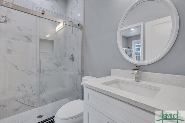 bathroom featuring a shower with door, vanity, and toilet