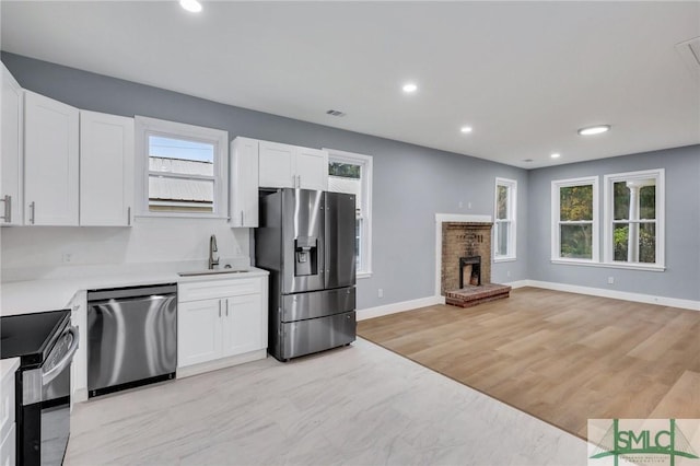 kitchen featuring a healthy amount of sunlight, sink, stainless steel appliances, and light wood-type flooring