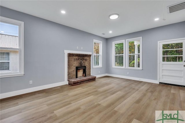 unfurnished living room featuring light hardwood / wood-style floors and a brick fireplace