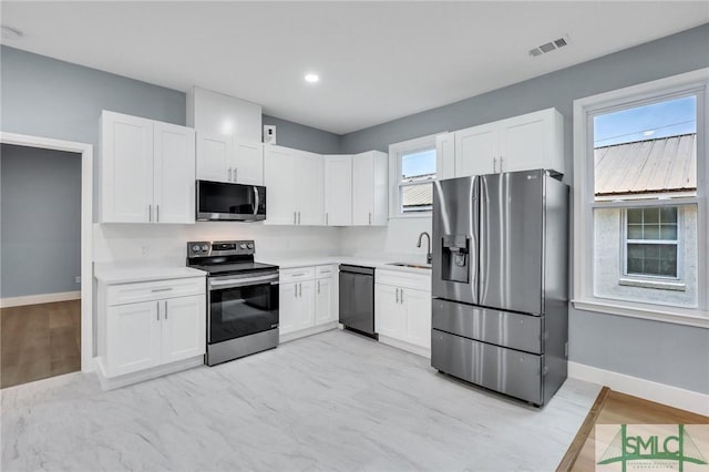 kitchen with stainless steel appliances, white cabinetry, plenty of natural light, and sink