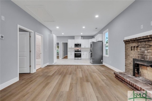 unfurnished living room featuring a brick fireplace and light hardwood / wood-style flooring